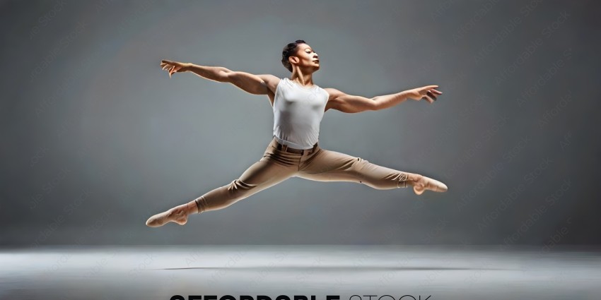 A male dancer in a white shirt and tan pants leaps into the air