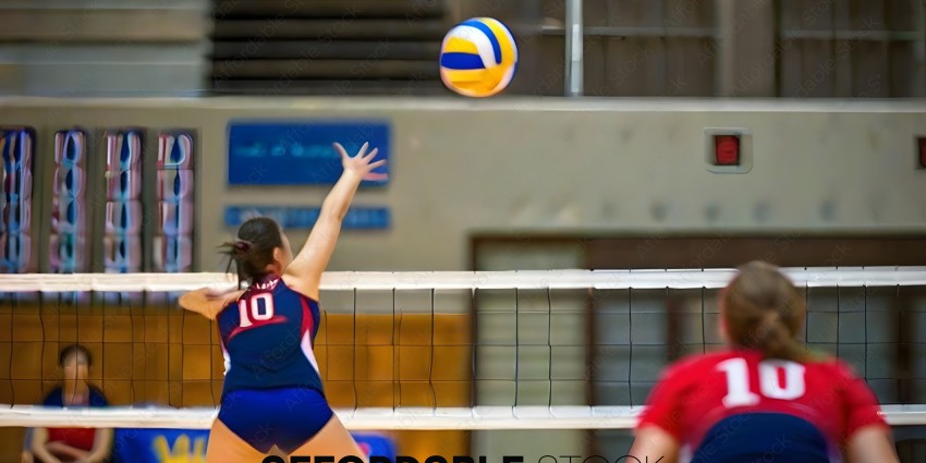 A woman in a blue and red uniform is jumping to hit a volleyball