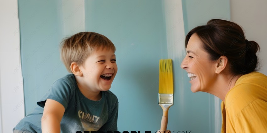 A woman and a child laughing while painting a wall