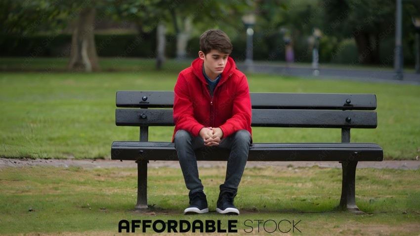 A young man in a red jacket sits on a bench