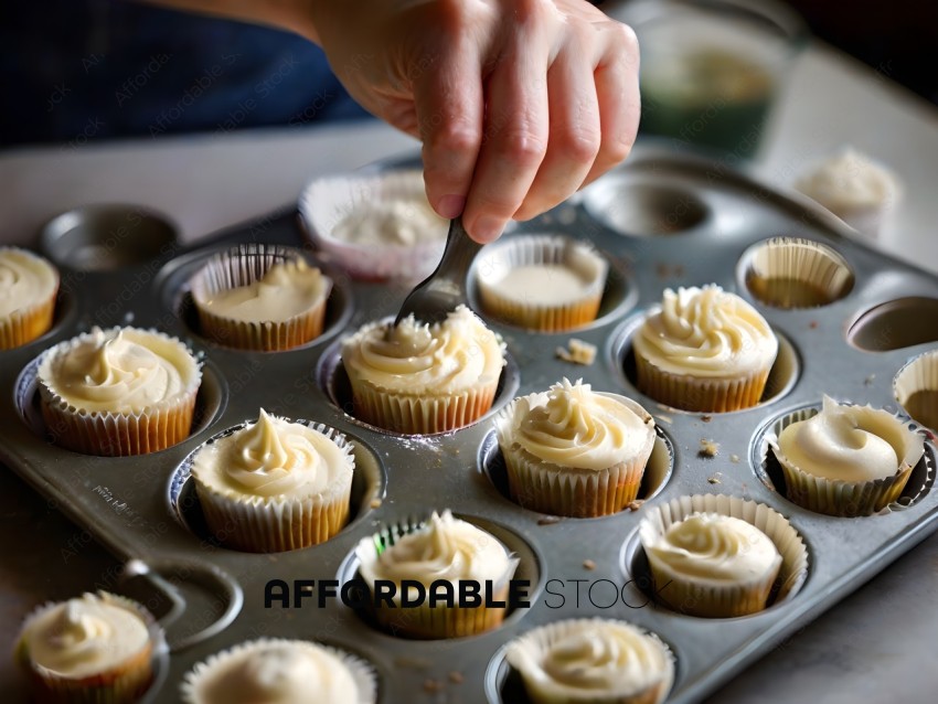 A person is using a spoon to scoop frosting into cupcakes
