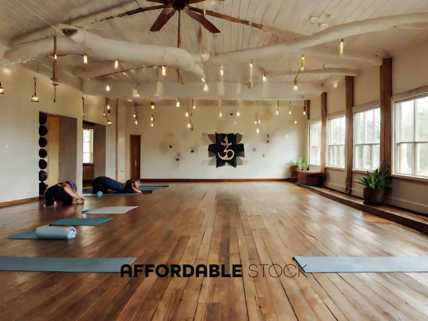 Yoga practitioners in a large room with wood floors and a ceiling fan
