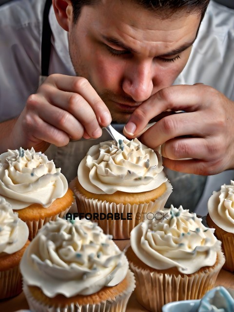 A man decorating cupcakes with white frosting and sprinkles