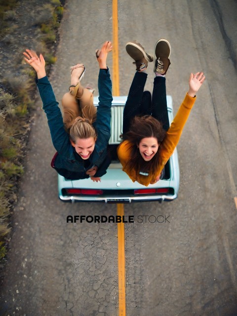 Two girls jumping in the air with a car in the background