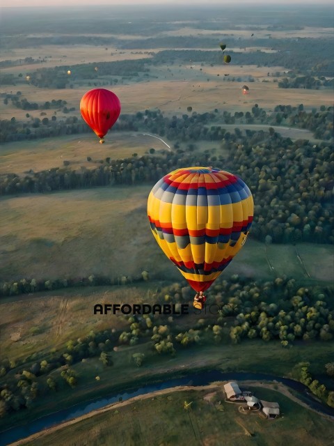 A hot air balloon with a rainbow pattern is flying over a field