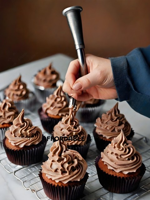 A person is frosting cupcakes with chocolate frosting