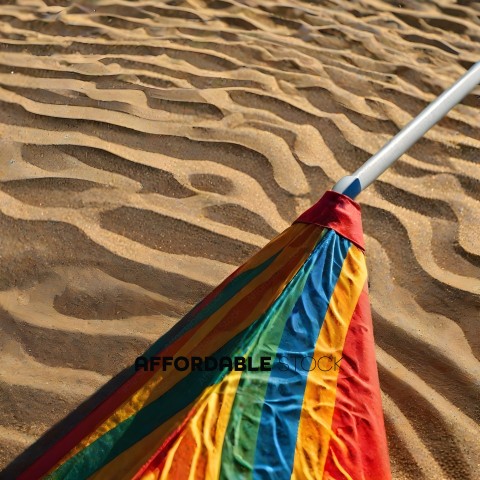 A rainbow colored umbrella in the sand