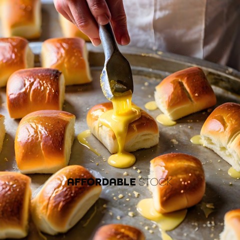 A person is dipping bread rolls into melted butter