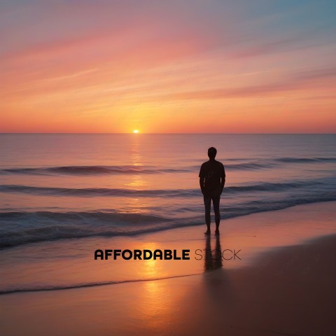 A man standing on the beach watching the sunset